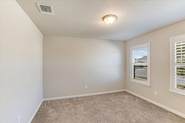 carpeted empty room featuring visible vents, baseboards, and a textured ceiling