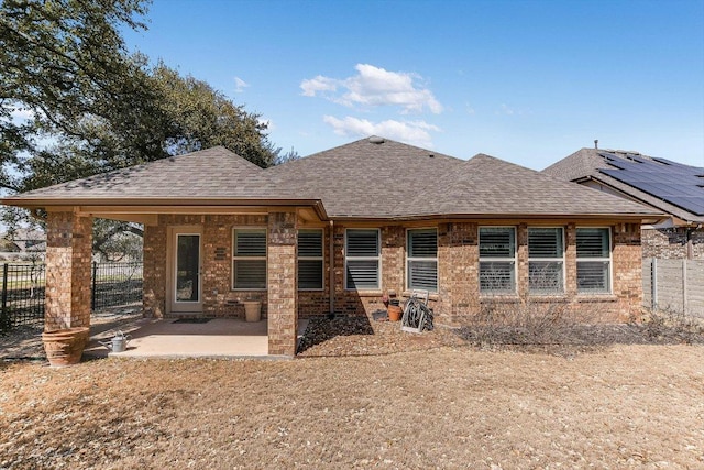 back of house with brick siding, a patio area, fence, and a shingled roof