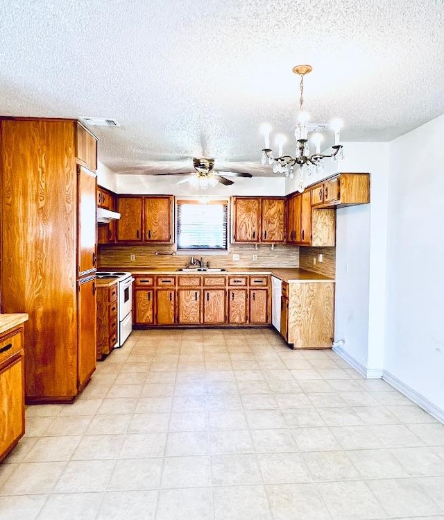 kitchen with white range with electric cooktop, dishwashing machine, brown cabinets, ceiling fan with notable chandelier, and a sink