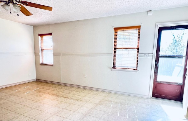 empty room featuring a ceiling fan, light floors, and a textured ceiling