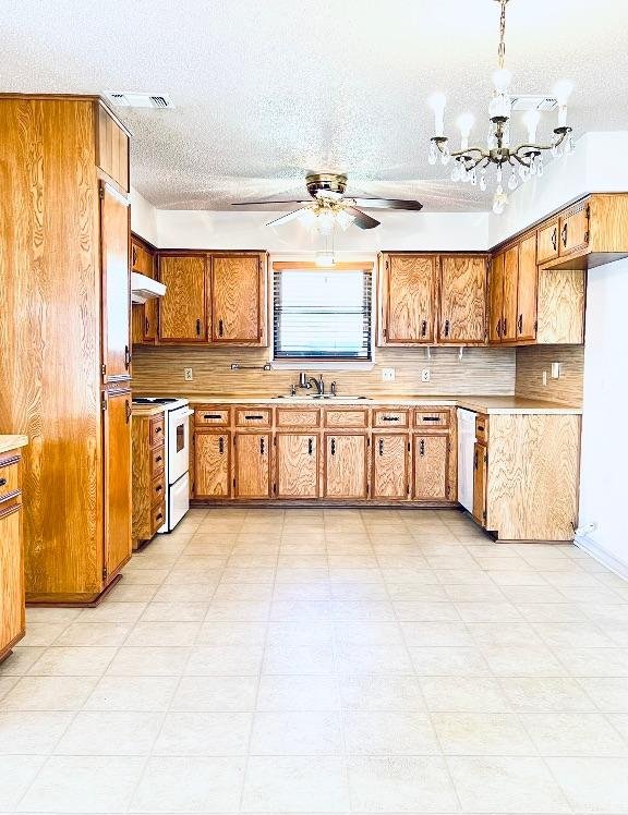 kitchen featuring electric range, visible vents, ceiling fan with notable chandelier, brown cabinetry, and light countertops