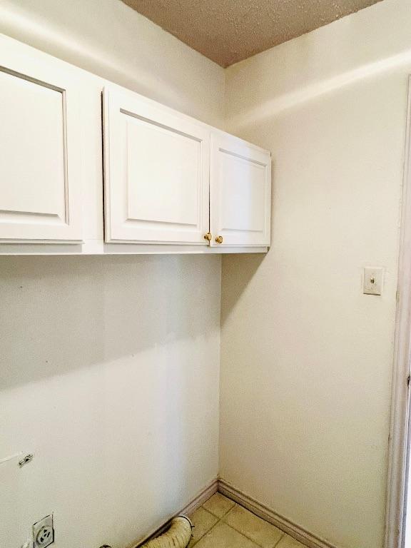 laundry area featuring electric dryer hookup, baseboards, and cabinet space