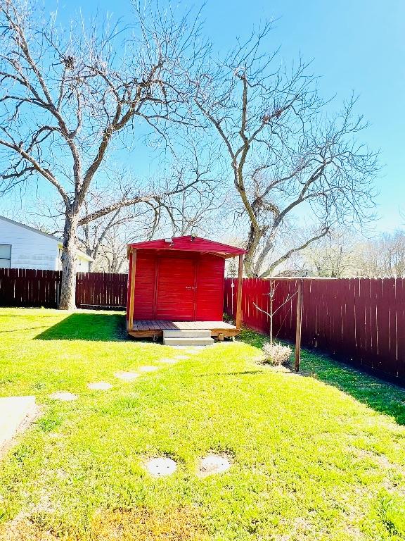 view of yard featuring an outbuilding, a fenced backyard, and a shed