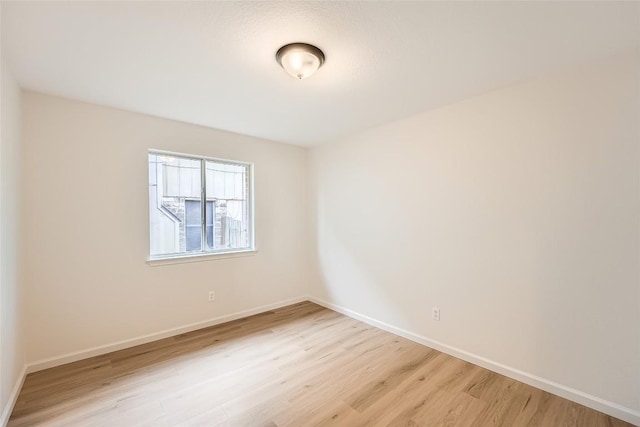 unfurnished room featuring baseboards and light wood-style floors