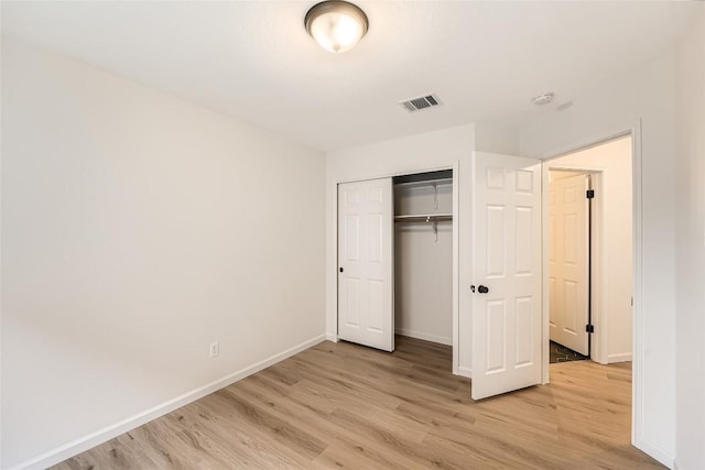 unfurnished bedroom featuring light wood-type flooring, visible vents, baseboards, and a closet