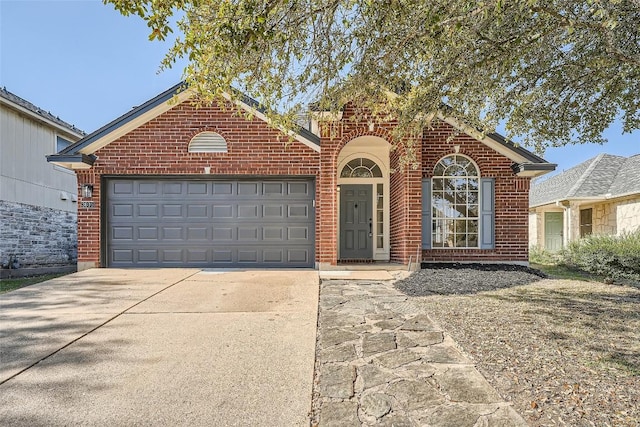 view of front of house with a garage, brick siding, and driveway