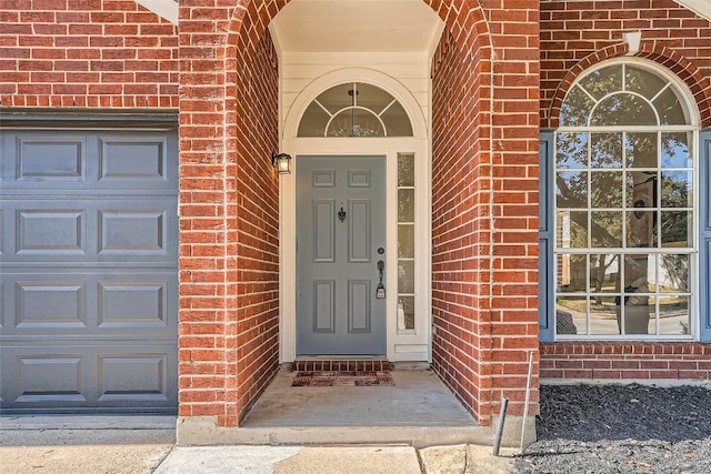 entrance to property with an attached garage and brick siding