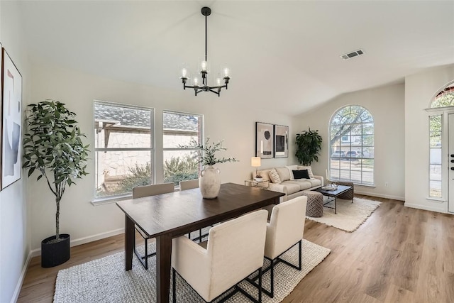 dining area with lofted ceiling, a notable chandelier, light wood-style floors, and visible vents