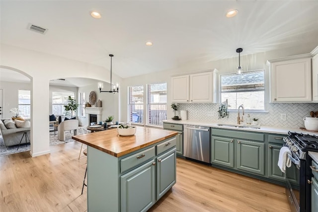 kitchen featuring green cabinets, open floor plan, arched walkways, stainless steel appliances, and a sink