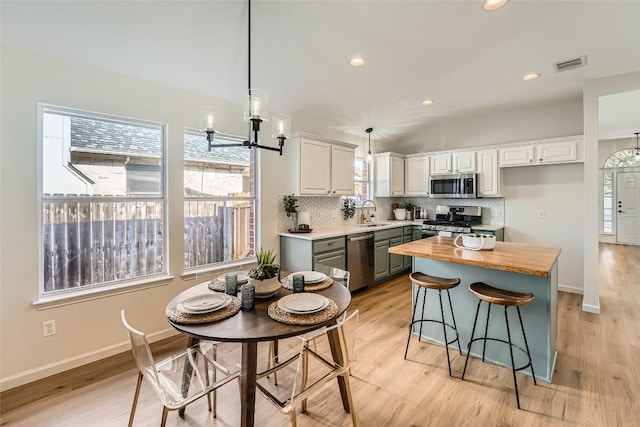 kitchen featuring light wood finished floors, visible vents, backsplash, and stainless steel appliances