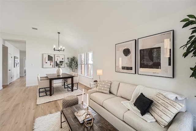 living area featuring light wood-type flooring, visible vents, baseboards, a chandelier, and vaulted ceiling