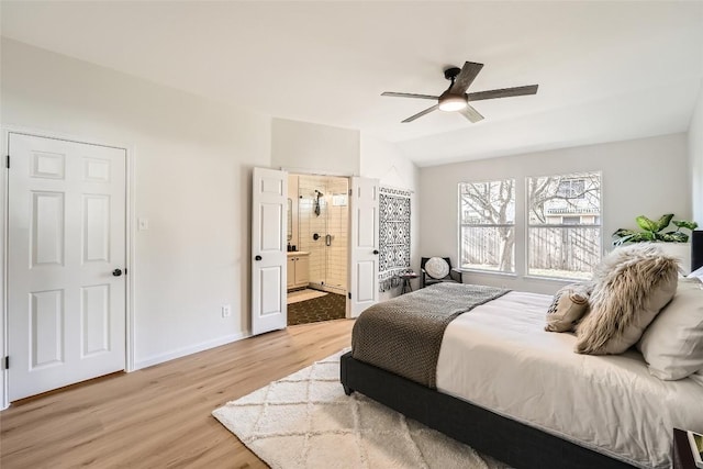 bedroom with baseboards, ensuite bath, light wood-style flooring, ceiling fan, and vaulted ceiling