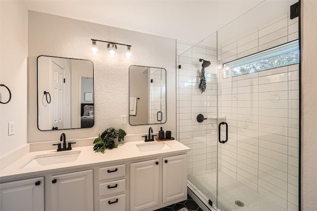 bathroom with double vanity, a stall shower, a textured wall, and a sink