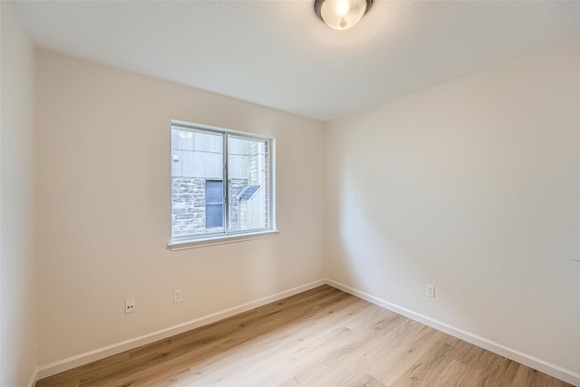 unfurnished room with baseboards and light wood-style floors