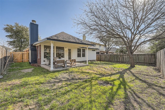 back of house with a patio, a yard, a fenced backyard, and a chimney