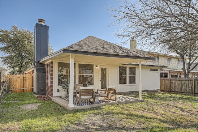 rear view of property featuring a yard, a fenced backyard, and a chimney