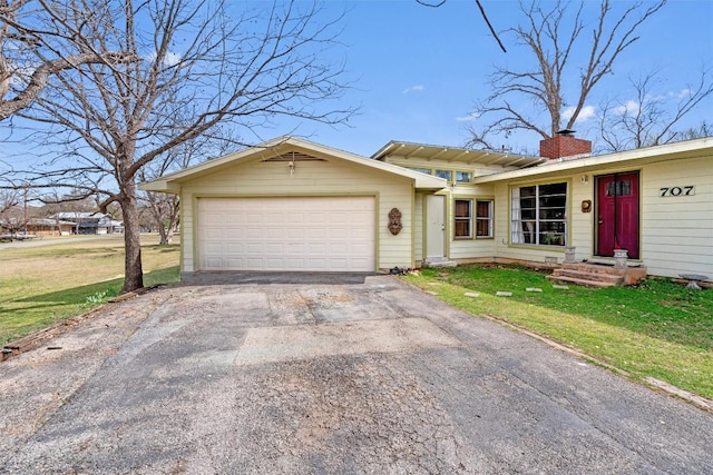 ranch-style home featuring aphalt driveway, a front yard, a garage, and a chimney