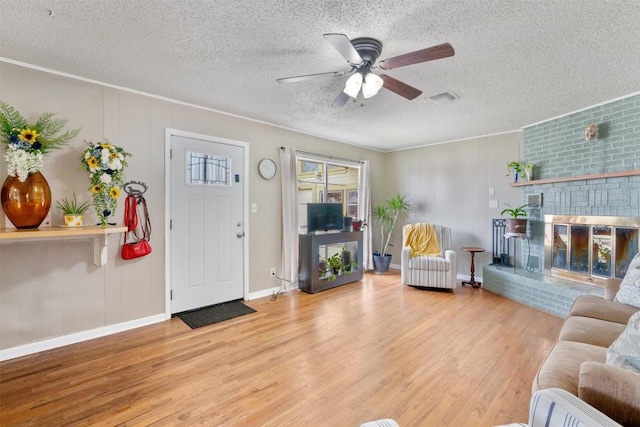 707 Sandy Harbor Dr, Horseshoe Bay, TX 78657 - living area featuring wood finished floors, a ceiling fan, a fireplace, and a textured ceiling