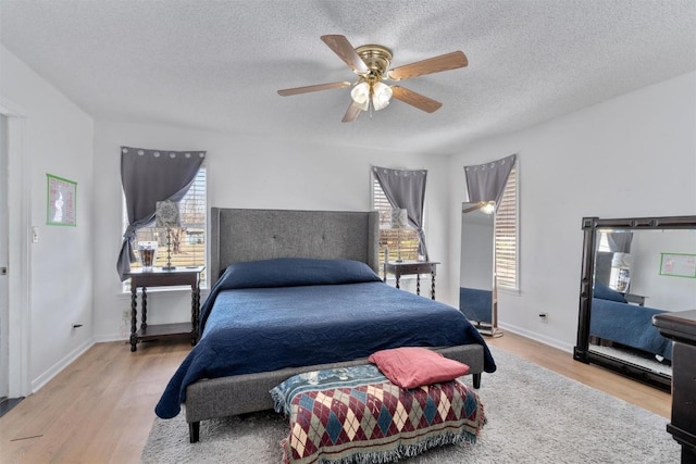 bedroom featuring baseboards, a textured ceiling, wood finished floors, and a ceiling fan