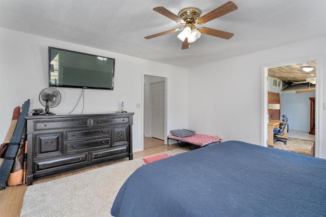 bedroom with a ceiling fan, wood finished floors, and a textured ceiling