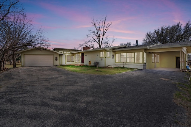 single story home featuring an attached carport, a garage, driveway, and a chimney