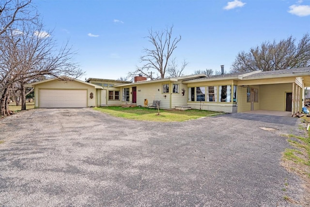 ranch-style house featuring aphalt driveway, an attached garage, a chimney, and a carport