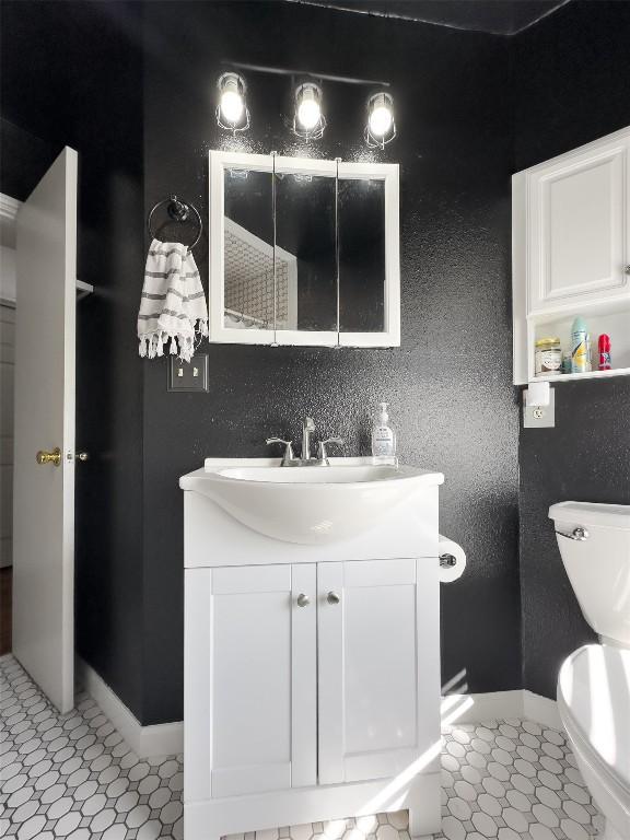 bathroom featuring tile patterned floors, baseboards, toilet, and vanity