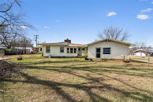 back of property with a lawn, a chimney, and fence