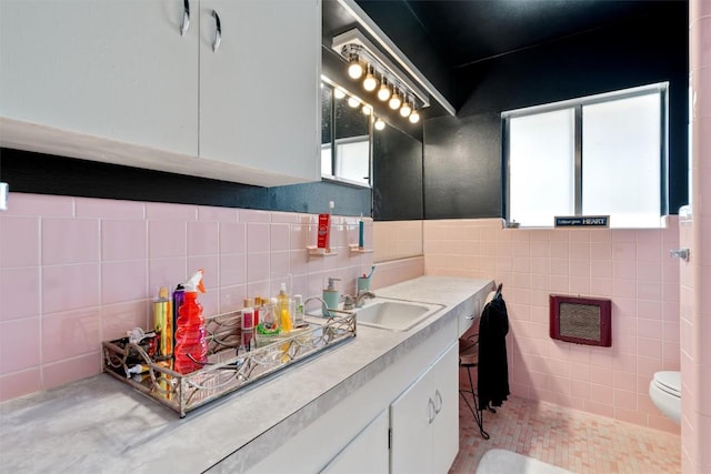 bathroom featuring tile patterned floors, toilet, tile walls, wainscoting, and vanity