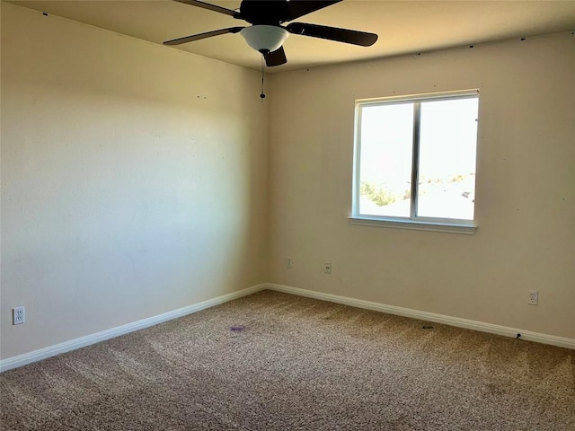 carpeted spare room with a ceiling fan and baseboards