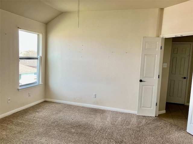 carpeted spare room with tile patterned floors, baseboards, and lofted ceiling