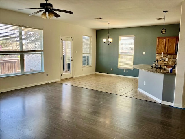 1118 Henderson Dr, Leander, TX 78641 - unfurnished living room featuring wood finished floors, a chandelier, and a ceiling fan