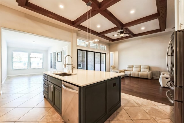 kitchen with open floor plan, an island with sink, a sink, ceiling fan with notable chandelier, and stainless steel appliances