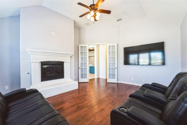 living room with a ceiling fan, french doors, visible vents, wood finished floors, and a glass covered fireplace