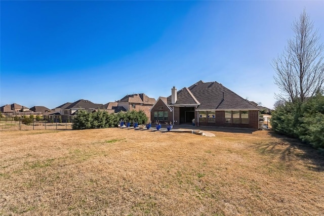 back of property featuring a lawn, a patio area, fence, and a chimney