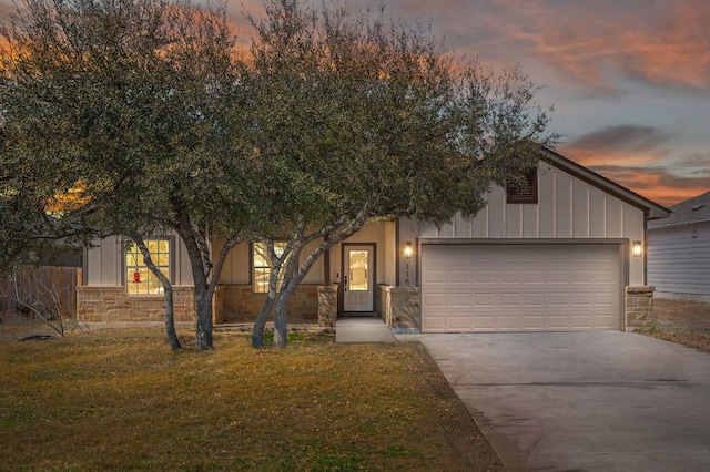 view of front of property featuring concrete driveway, a garage, stone siding, a lawn, and board and batten siding