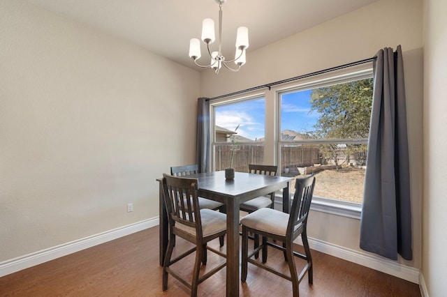 dining space with baseboards, an inviting chandelier, and wood finished floors