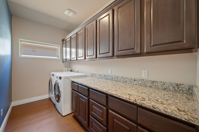 laundry room with cabinet space, baseboards, light wood-style floors, and separate washer and dryer