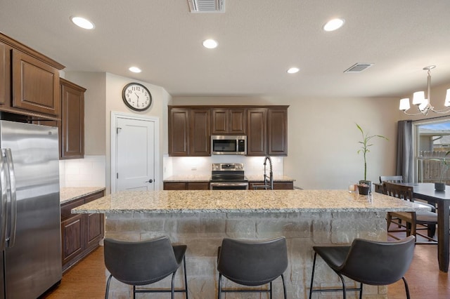 kitchen with a breakfast bar, visible vents, appliances with stainless steel finishes, and a chandelier