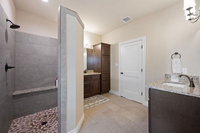 bathroom with baseboards, visible vents, two vanities, a sink, and a walk in shower