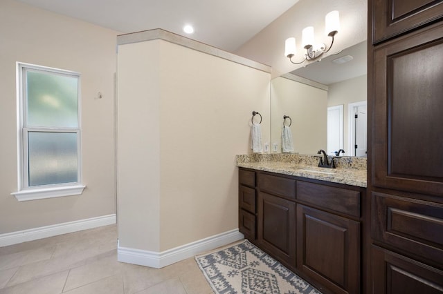 bathroom with tile patterned flooring, a notable chandelier, vanity, and baseboards