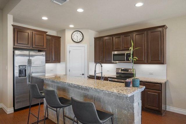 kitchen featuring decorative backsplash, stainless steel appliances, and light stone countertops