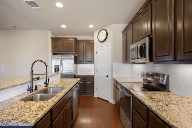 kitchen with visible vents, a sink, decorative backsplash, stainless steel appliances, and dark brown cabinets