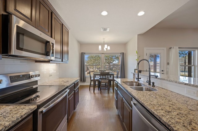 kitchen featuring visible vents, an inviting chandelier, a sink, stainless steel appliances, and backsplash