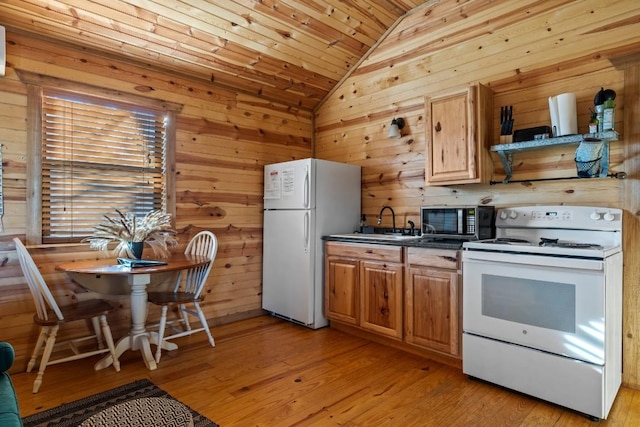 kitchen with white appliances, light wood-style floors, lofted ceiling, and wooden walls