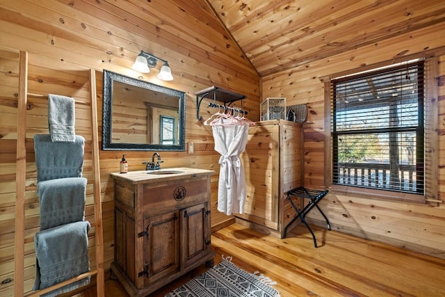 bathroom with vanity, lofted ceiling, wooden walls, and wood finished floors