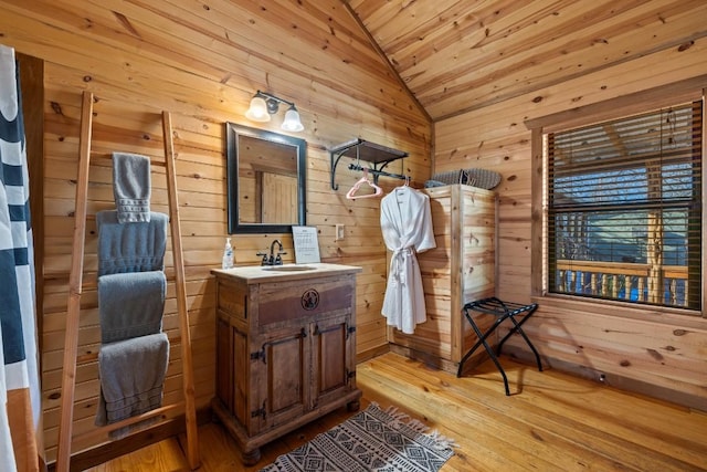 bathroom with vanity, lofted ceiling, hardwood / wood-style flooring, and wood walls