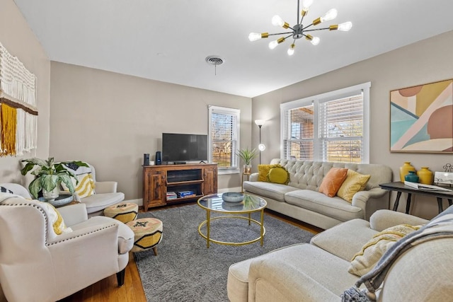 living room featuring an inviting chandelier, wood finished floors, visible vents, and baseboards