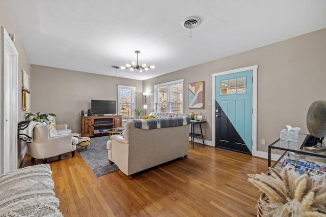 living room with visible vents, baseboards, an inviting chandelier, and wood finished floors