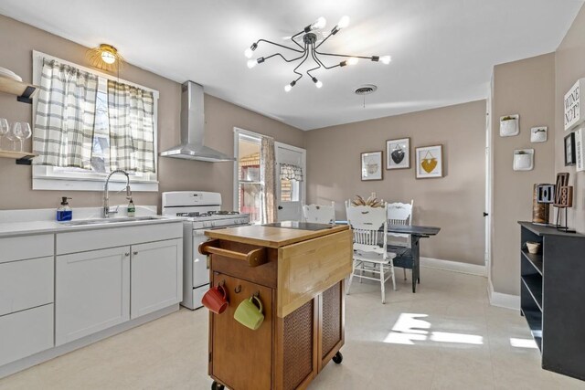 kitchen featuring visible vents, a sink, gas range gas stove, wall chimney exhaust hood, and open shelves